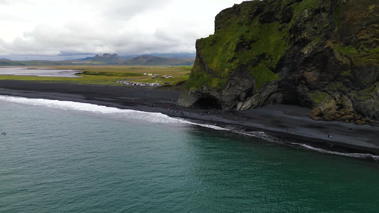4K Cinematic drone shot over Reynisfjara Beach, capturing the contrast between the dark volcanic shore, turquoise waves, and dramatic cliffs under moody Nordic skies - Iceland_32