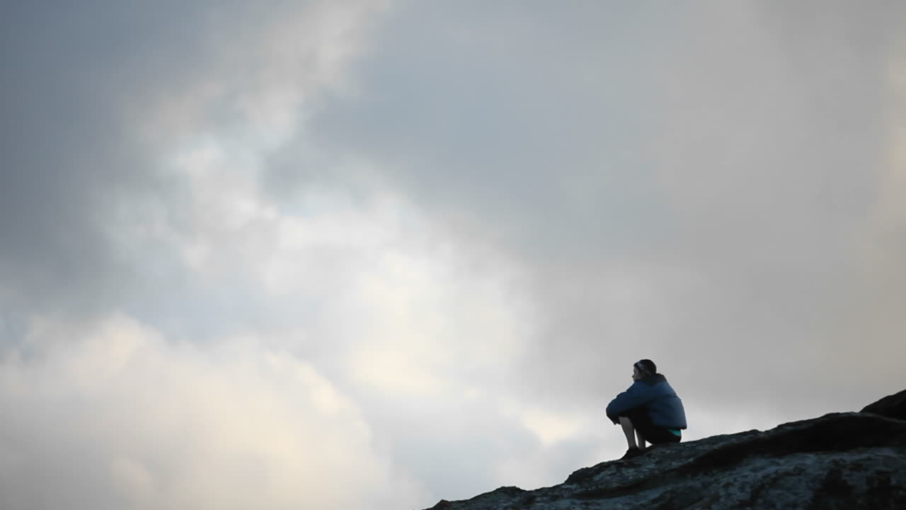 un hombre se sienta encima de un área elevada y contempla la vista