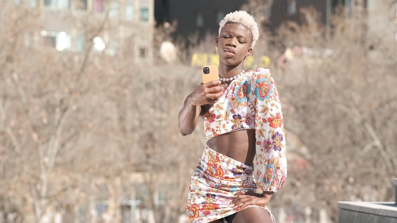 Trendy black queer person in dress taking selfie on street