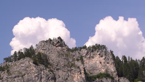 close up shot of beautiful cliffs with high clouds and few trees on clear blue sky day