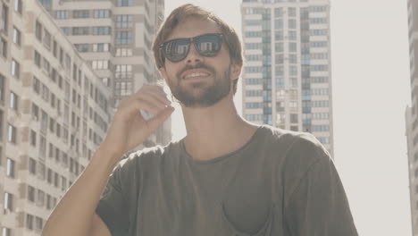 man in sunglasses in front of city buildings