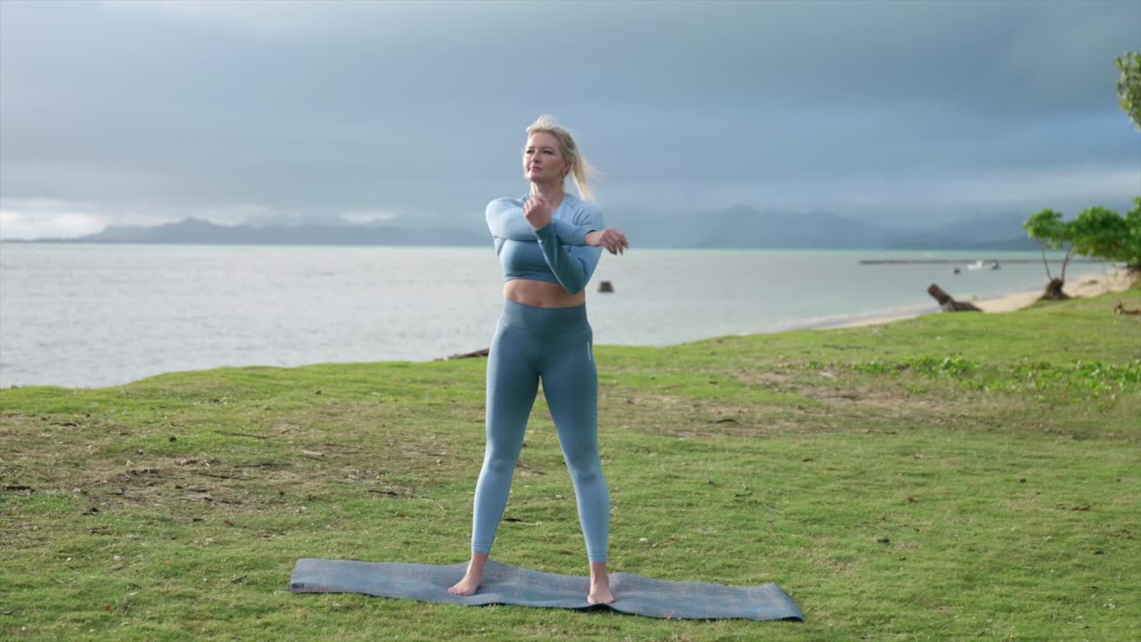 Female stretching in fitness outfit by the beach
