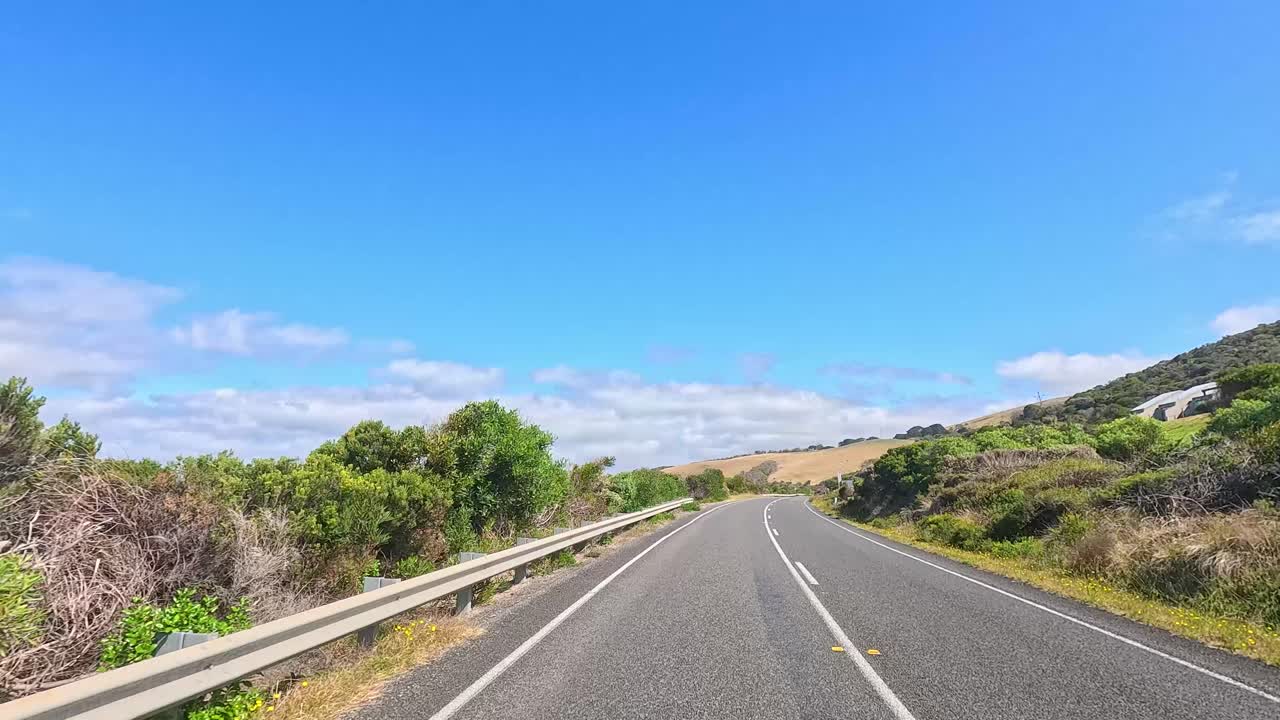 A serene drive along Great Ocean Road with coastal views, lush greenery, and clear blue skies captured in vibrant daylight