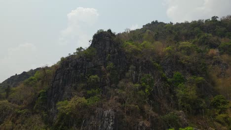 4k-Luftgleitlandschaftsaufnahmen,-Die-Im-Sommer-An-Ruhigen,-Sonnigen-Tagen-In-Thailand,-Südostasien,-Grünen,-üppigen-Wald-Auf-Der-Klippe-Des-Kalksteinbergs-Einfangen