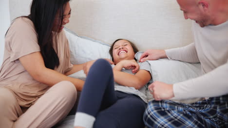 happy, tickling and parents with child on bed