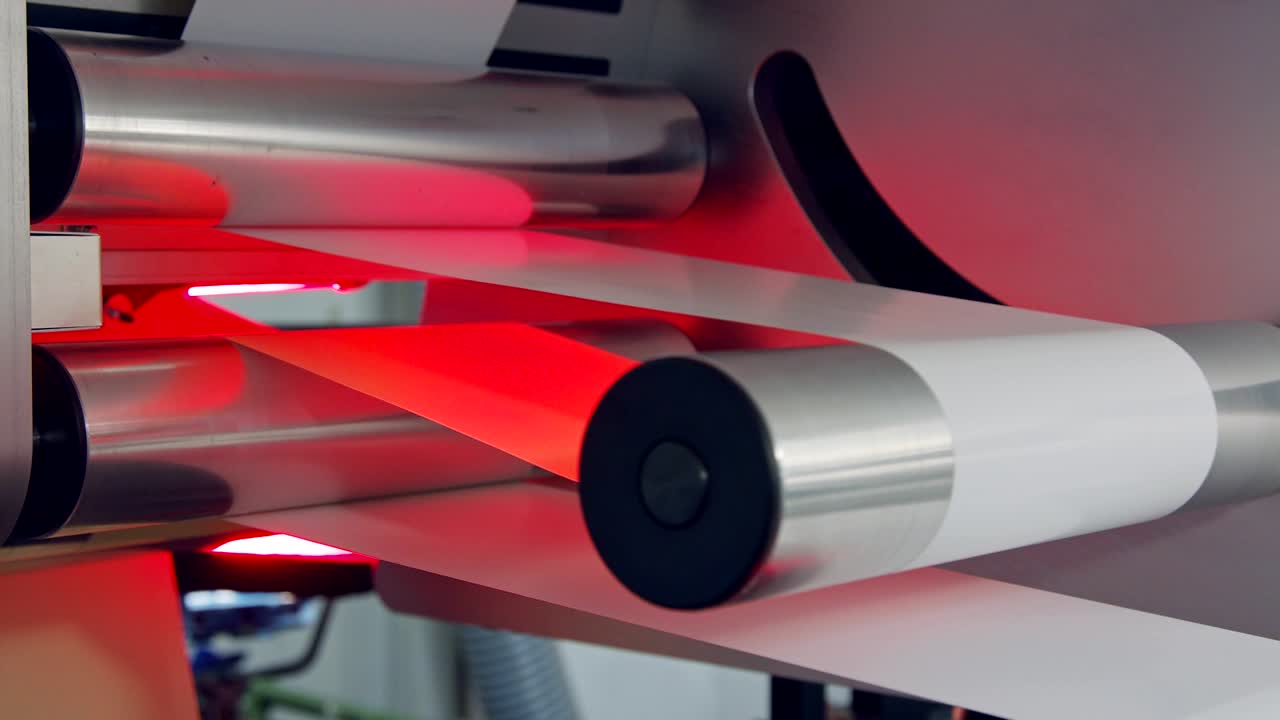 Closeup on paper moving through a large industrial printing machine