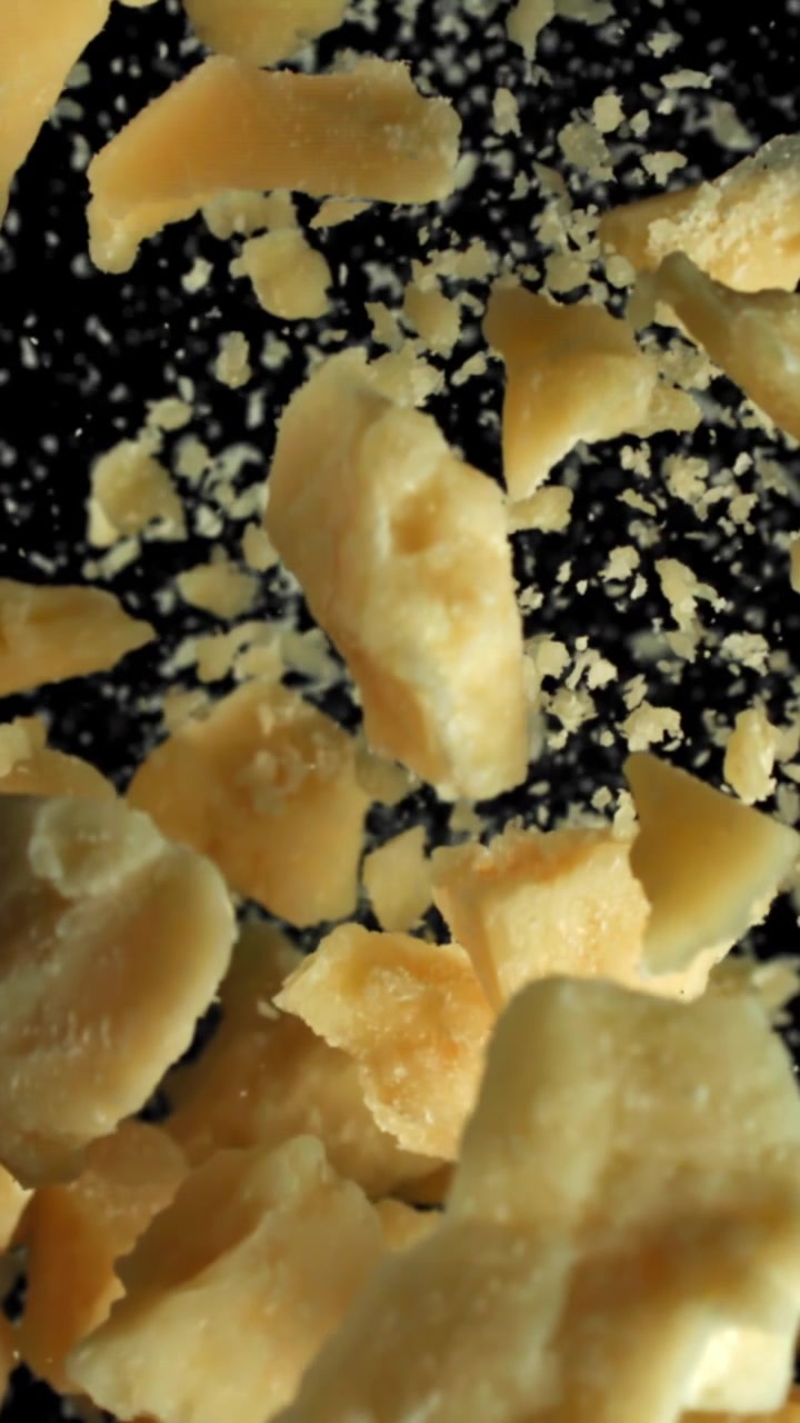Slow Motion of Grated Parmesan Cheese Falling on Black Background