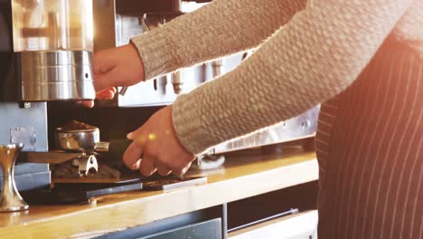 Waiter-using-coffee-grinder-to-grind-coffee-beans