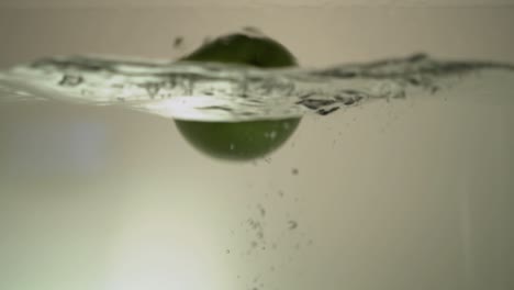 una manzana cae pesadamente al agua y permanece en la superficie del agua
