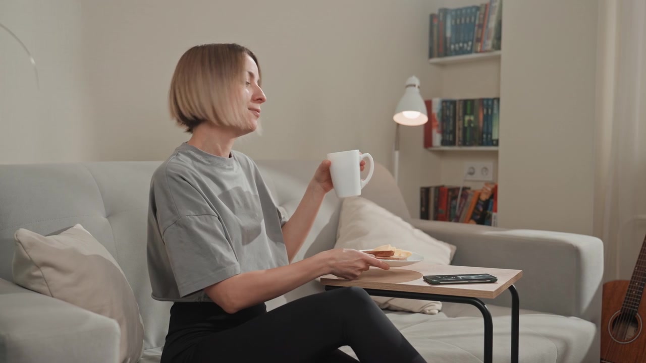 Scena di caffè mattutino in un accogliente soggiorno che mostra un amante della musica che si gode una colazione tranquilla sul divano. Giovane cantautore che sfoglia spartiti, studente che sfoglia un libro, panettiere che assaggia un dolce, lavoratore a distanza che controlla.