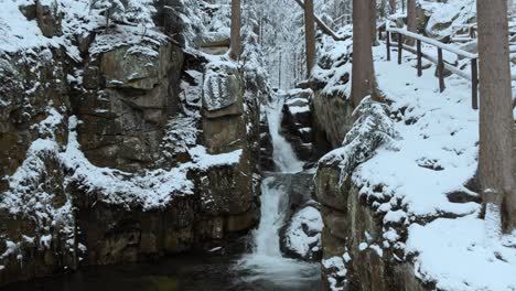 aerial view of a waterfall, in the karkonosze mountains, on a cloudy, winter day, in poland - rising, drone shot