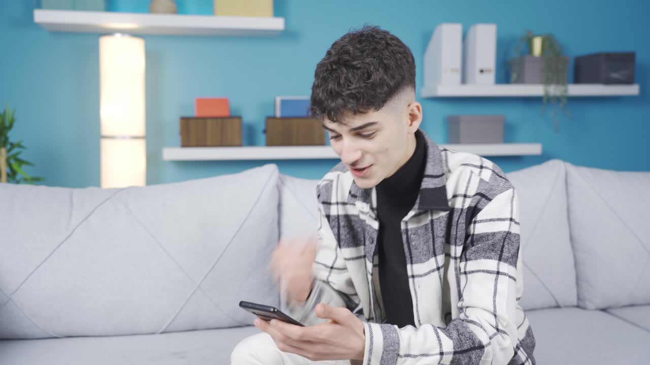 젊은 남자는  ⁇ 드폰을 쳐다보고, 놀랐고 행복했습니다. 그는 좋은 소식을 얻었습니다.