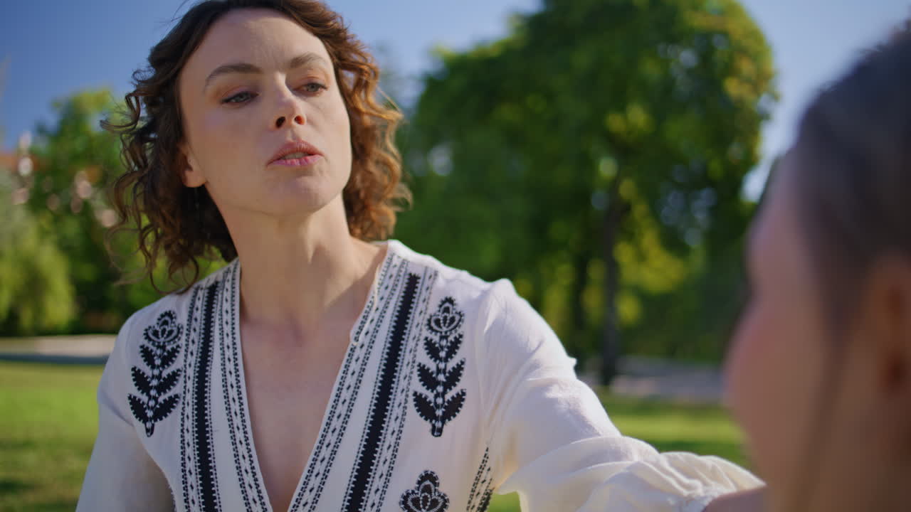 Mom child sitting grass talking together closeup. Woman girl enjoying summer