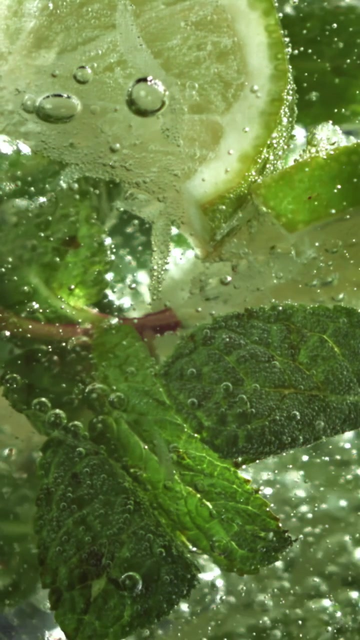Primo piano macro di lime fresco e menta in acqua frizzante.