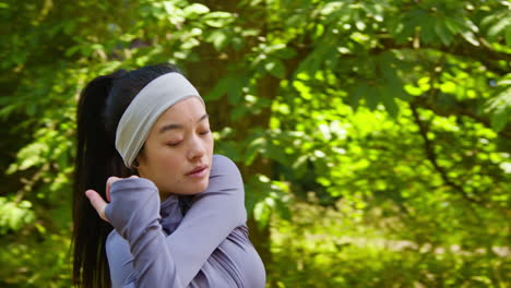 Young-Woman-Stretching-Before-Exercising-Running-Through-City-Park-Wearing-Wireless-Earbuds-4