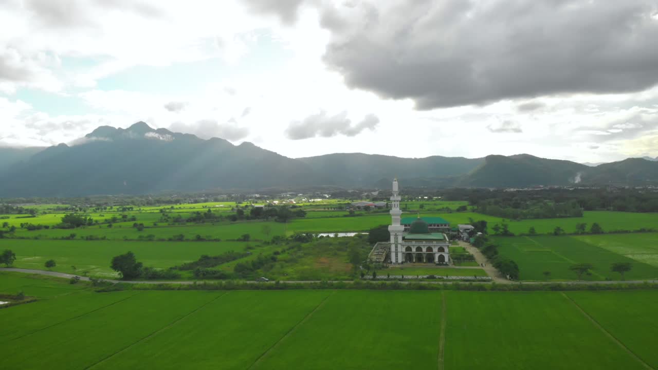 이슬람 모스크는 고립된 땅, 녹색 풀, 산의 배경 태국, 공중 드론, 천천히 떨어지고, 낮, 밝은 구름 날.