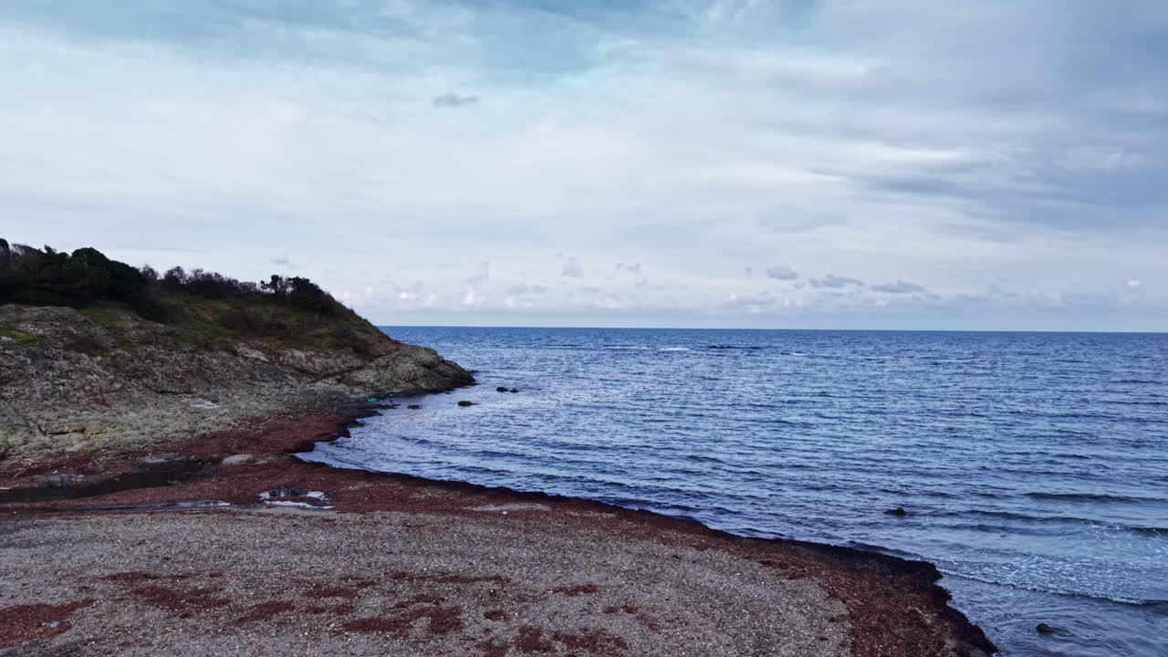 Klidný pobřežní pohled na tichou řeku, která se vlévá do klidného moře pod nekonečnou oblohou