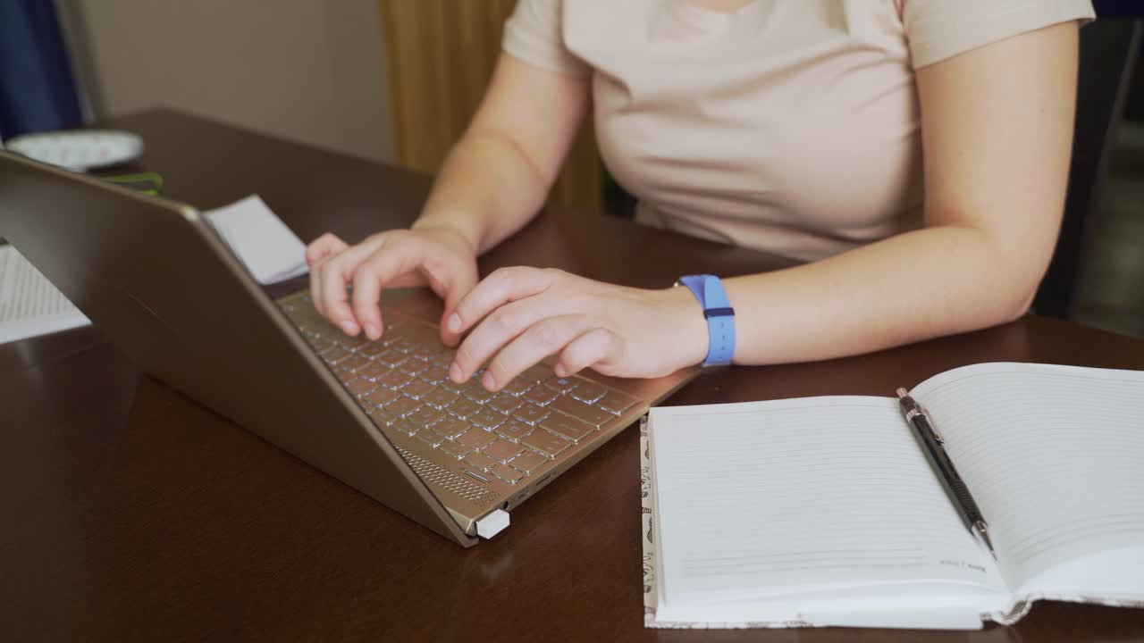 las manos femeninas están escribiendo texto en el teclado de la computadora portátil. los dedos presionan rápidamente las teclas del teclado. hay un cuaderno al lado. computadora personal, trabajo remoto en casa, negocios, estudio, mensajería, chat