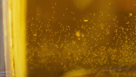 Extreme-Close-up-of-craft-Beer-bubbles-floating-to-the-top-of-a-pint-glass-with-foam-VERTICAL