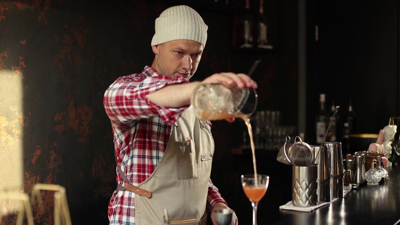 Professioneller Barkeeper bereitet einen Cocktail zu und schenkt ihn in einer modernen Bar ein