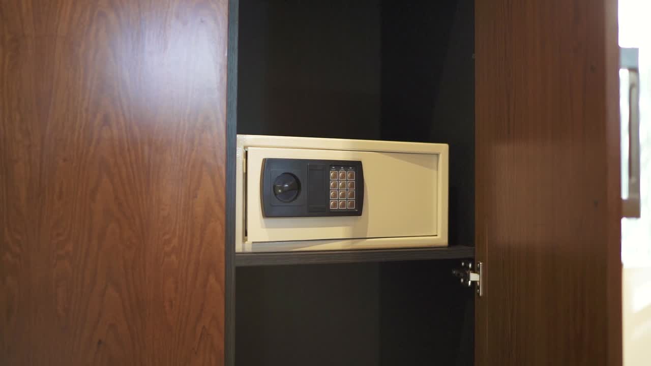 Open Wooden Wardrobe Displaying Secure Electronic Safe for Valuables in Modern Hotel Room.