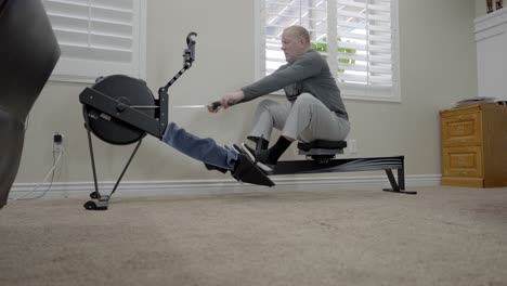 senior man rowing machine exercise - sliding low angle