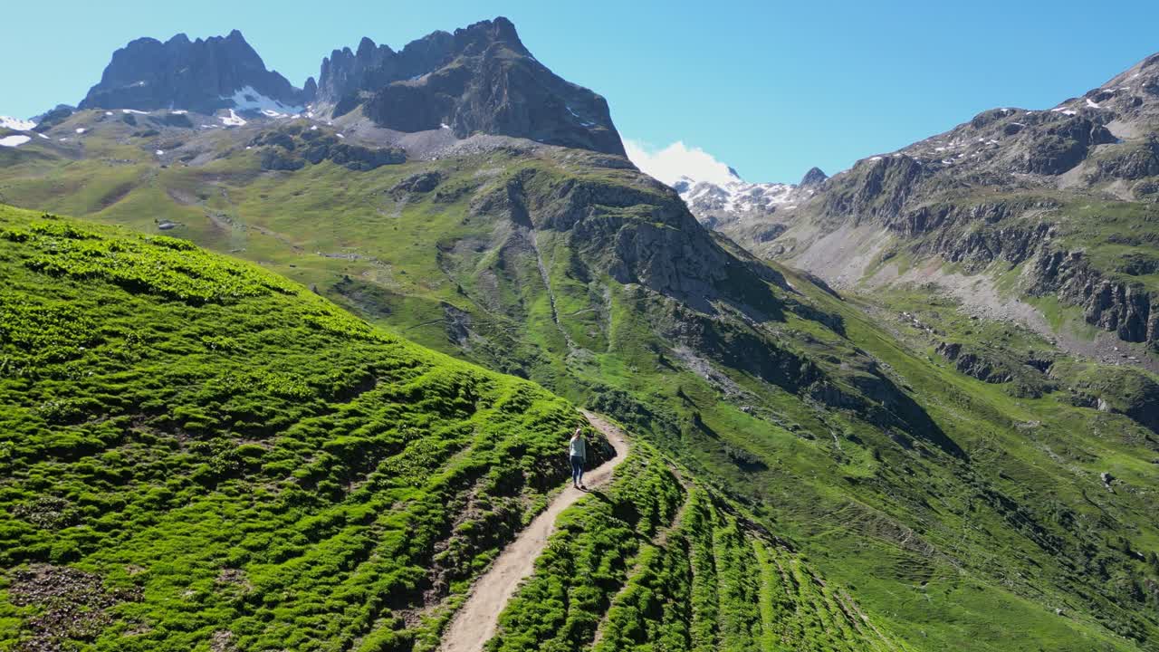mujer adulta joven camina por senderos en el valle verde en los alpes franceses - seguimiento de la muñeca aérea
