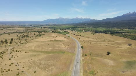 Muñeca-Aérea-Siguiendo-Un-Camino-Rural-Solitario-Con-Montañas-De-Fondo-Durante-El-Día