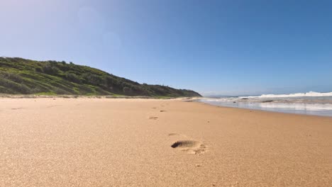 footprints on sandy beach with ocean waves