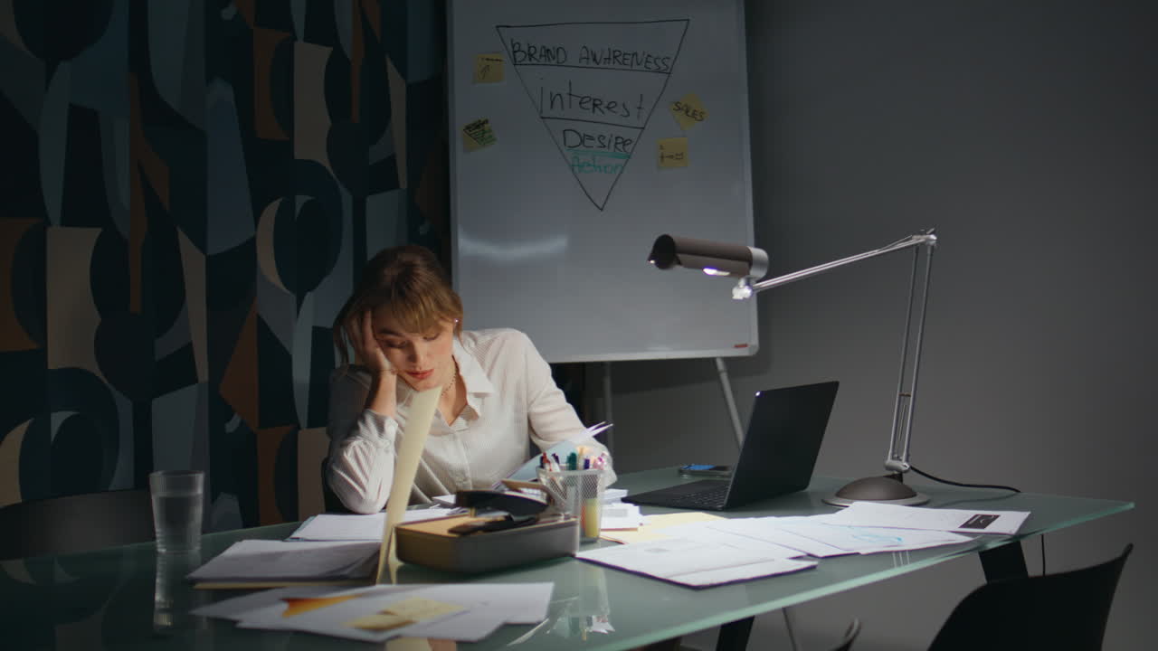 Tired secretary doing paperwork working night. Overworked woman checking papers
