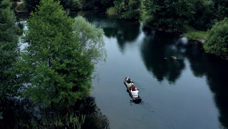 Drone-Rastreando-A-Un-Par-De-Hombres-Navegando-En-Un-Bote-De-Madera-Dugot-En-Un-Río-De-Agua-Oscura