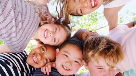 Low-Angle-Portrait-Looking-Up-Into-Faces-Of-Children-Hugging-Each-Other