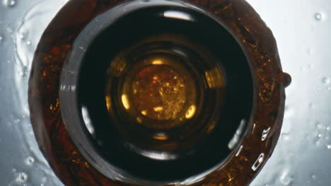 dark lager overflowing bottle closeup. unfiltered cool beverage splashing flask