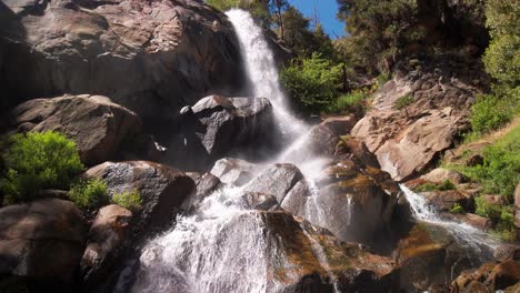 Panning-shot-from-below-mountain-waterfall-following-the-water-over-rocks