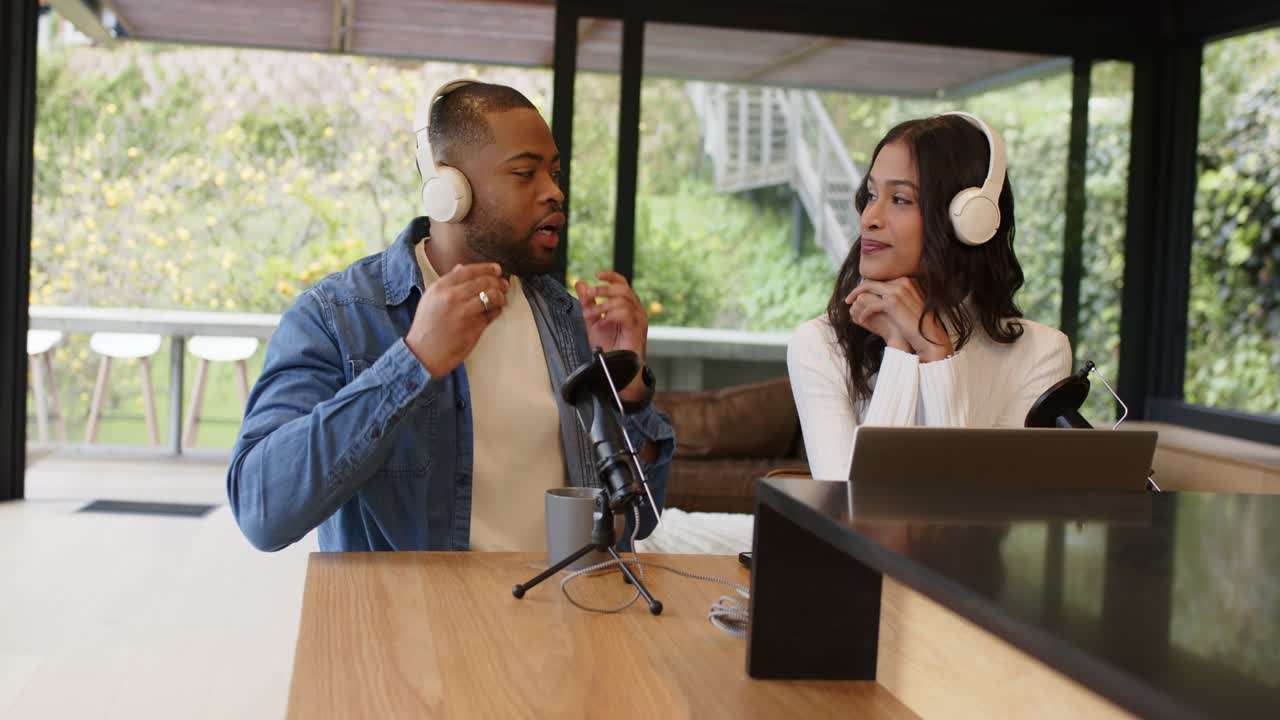 Co-conduttori di diversa etnia prendono cuffie bianche e ne regolano la calzata su un patio, iniziando un livestream del podcast.