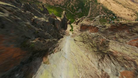 Fast-FPV-drone-shot-diving-down-to-rocky-slope-and-through-stone-gates