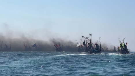 fishing boats in indian ocean during patik laut festival in muncar, banyuwangi, jawa, indonesia covered in smoke exhaust