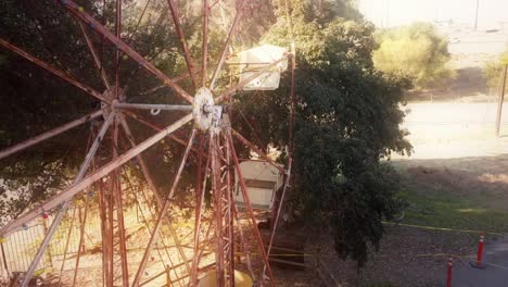 Luft-Um-Ein-Rostendes-Riesenrad,-Das-Sich-Zurückzieht,-Um-Einen-Verlassenen-Parkplatz-Und-Die-Spitze-Einer-Hohen-Palme-Freizulegen