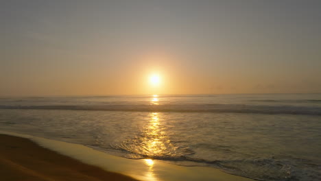 Slow-motion-drone-shot-of-a-colorful-sunset-above-a-calm-ocean-beach-at-Gillards'-beach