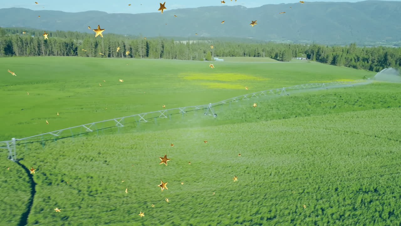 Pivot irrigation pipe crossing field diagonally, sprinklers spraying water and sparkles