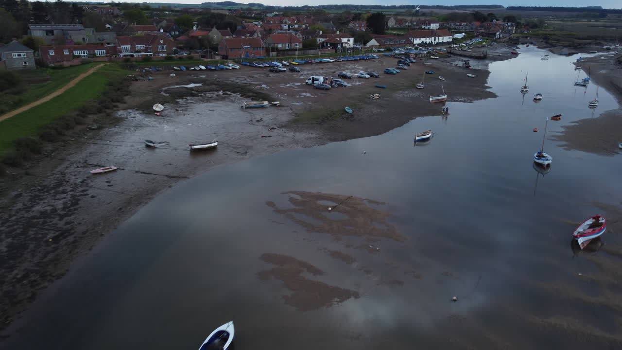 Aerial Drone Shot Flying Over Creek at Low Tide with Sailing Boats and Boathouse in Burnham Overy Staithe North Norfolk on Cloudy Gloomy Moody Day UK