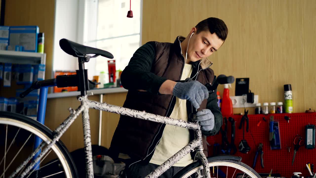 el mecánico se centra en el montaje de la bicicleta, la colocación del manillar, el apretamiento de las articulaciones con la llave y la escucha de música a través de auriculares.