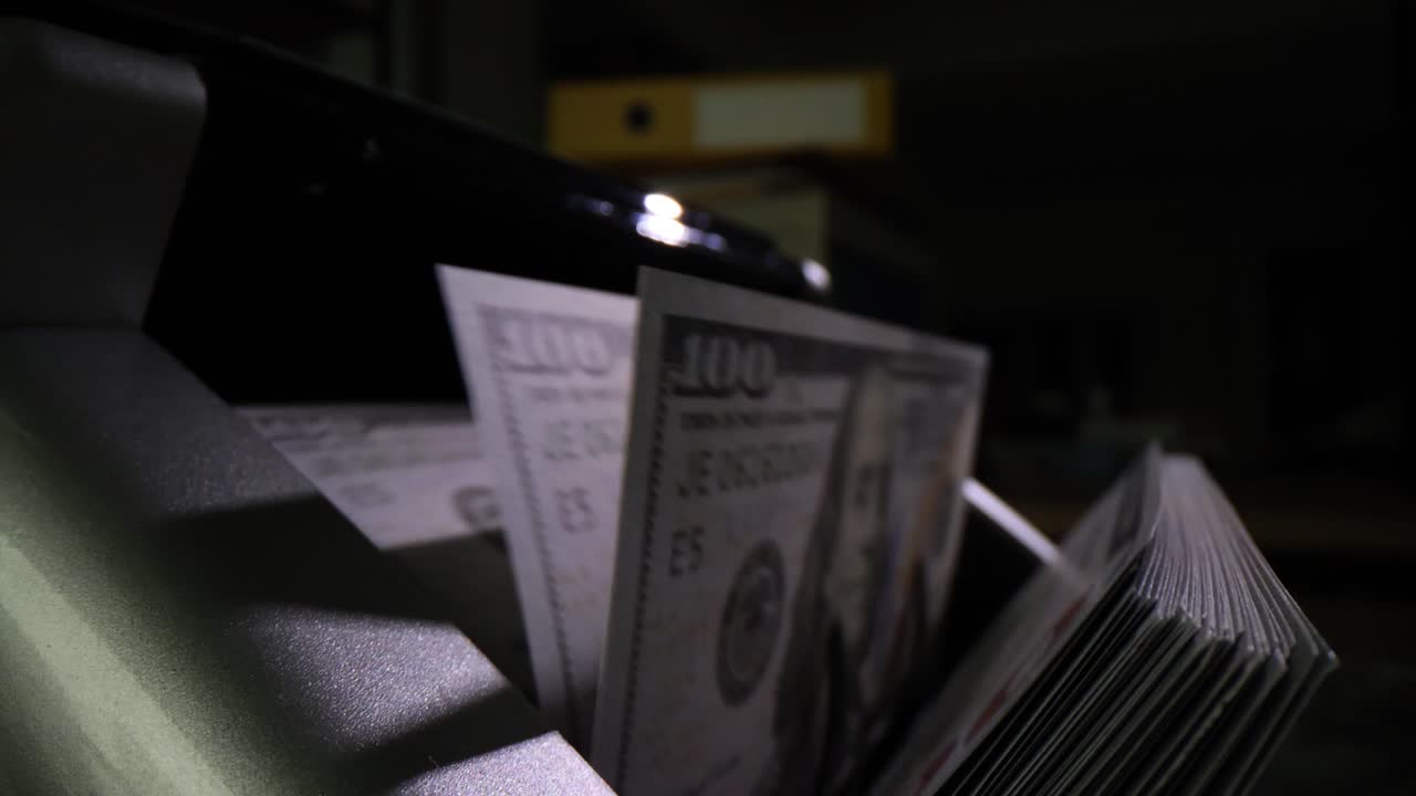 Bill counter operates with dollar banknotes in dark premise