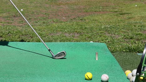 golf club hitting ball on green mat