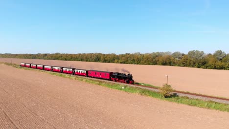 aéreo: ferrocarril de vía estrecha de vapor en el campo que pasa por campos sembrados