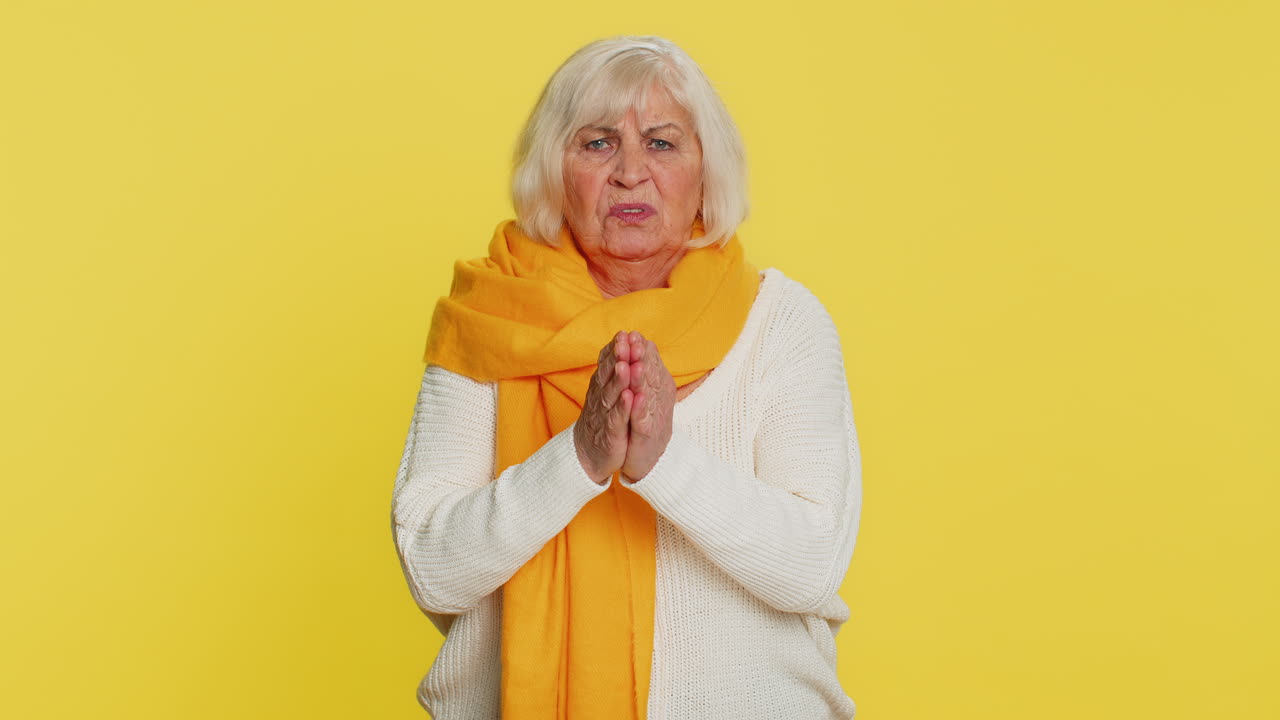 Senior old woman praying making wish, asking hopeful help, begging apology, meditation, imploring