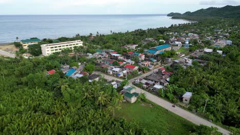 aerial overhead drone shot of quaint barangay with calm sea in background and lush greenery in catanduanes, philippines