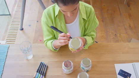 woman running online business from home labelling and smelling boutique candles before shipping