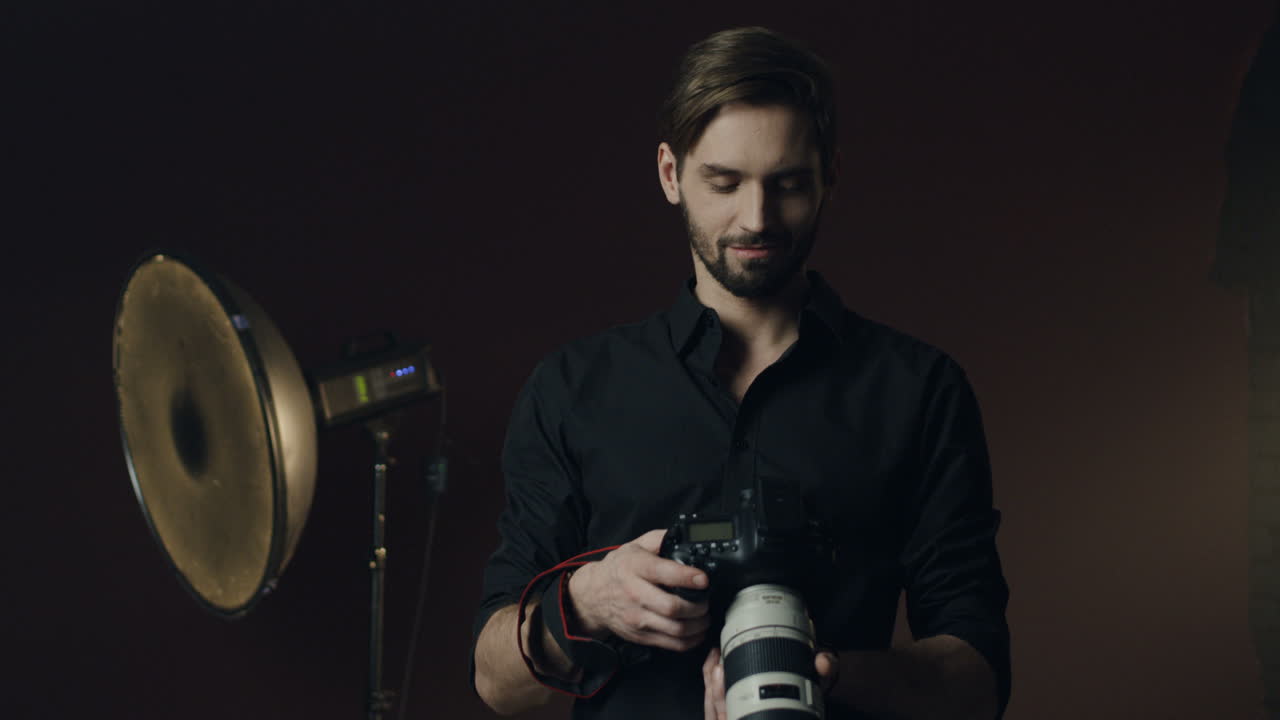 어두운 스튜디오에서 카메라 화면에 있는 사진을 보고 있는 백인 청년의 클로즈업 보기