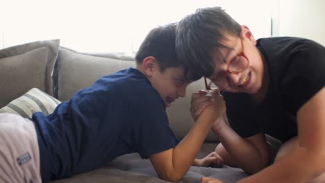 두 명의 백인 아이들이 집에서 armwrestling 게임을 즐기고 있습니다.